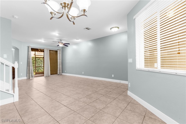 spare room featuring light tile patterned floors and ceiling fan with notable chandelier