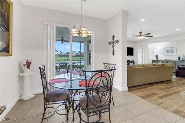 dining area with light tile patterned flooring and ceiling fan with notable chandelier