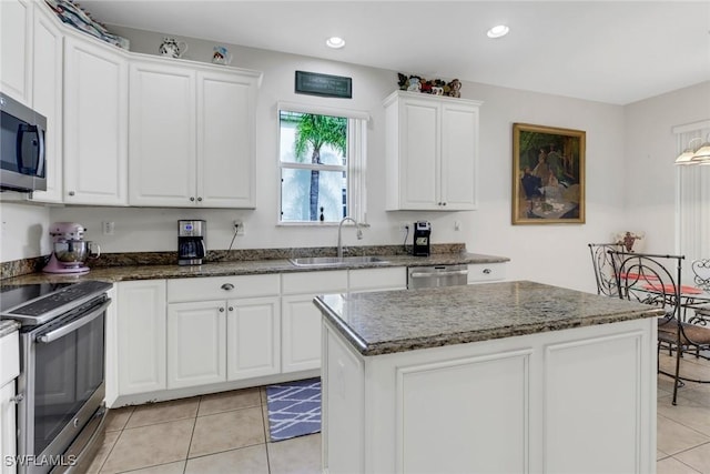 kitchen featuring white cabinetry, sink, a center island, light tile patterned floors, and appliances with stainless steel finishes