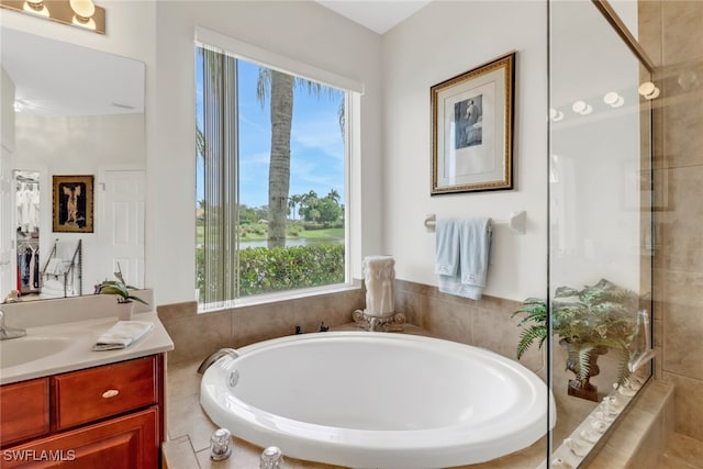 bathroom with vanity, a wealth of natural light, and a relaxing tiled tub