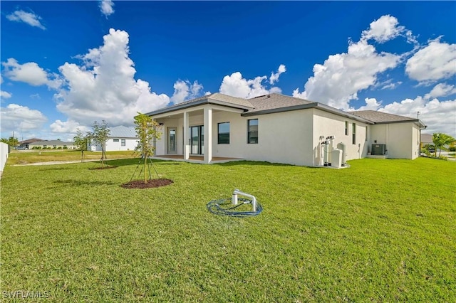 rear view of house featuring ac unit and a lawn