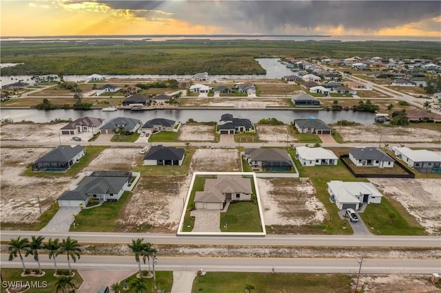 aerial view at dusk featuring a water view