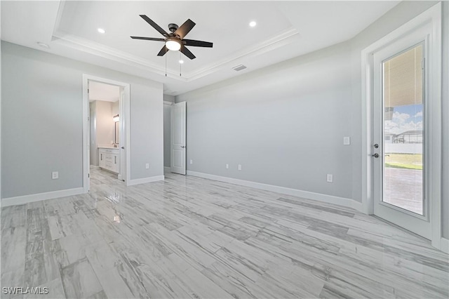 unfurnished bedroom featuring a raised ceiling, ensuite bath, ceiling fan, and access to outside