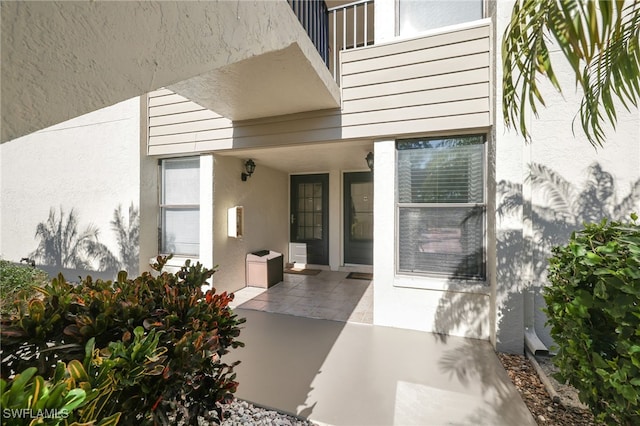 entrance to property featuring a balcony and stucco siding