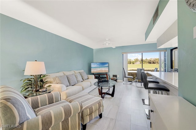 living area featuring ceiling fan, visible vents, and baseboards