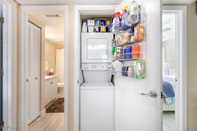 washroom with light hardwood / wood-style floors and stacked washer and dryer