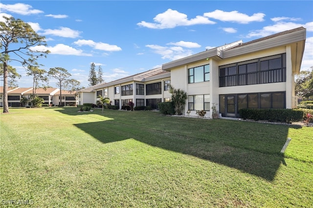 back of property featuring a lawn, a residential view, and stucco siding