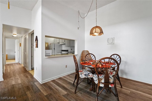 dining area featuring dark wood-type flooring and a high ceiling