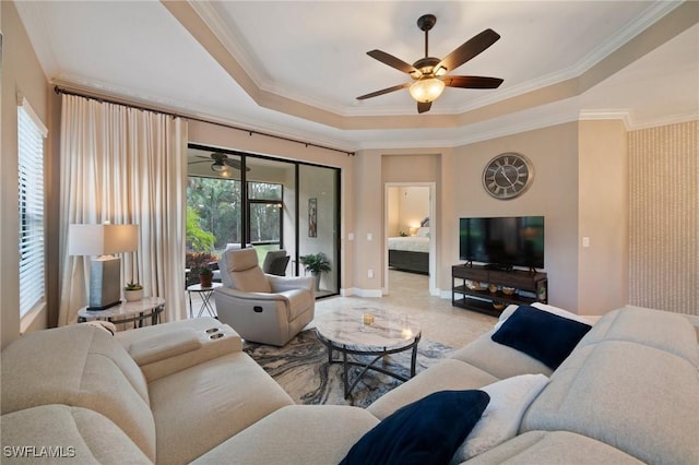 living room with a raised ceiling, ceiling fan, plenty of natural light, and crown molding