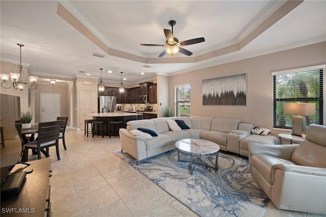 tiled living room featuring ceiling fan with notable chandelier, a raised ceiling, and a wealth of natural light