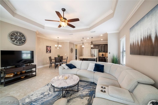 living room featuring ceiling fan with notable chandelier, a raised ceiling, and ornamental molding