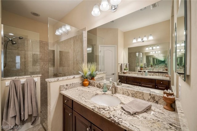 bathroom featuring a tile shower, vanity, and tile patterned flooring