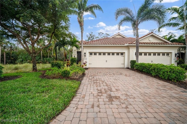 mediterranean / spanish-style home featuring a front lawn and a garage