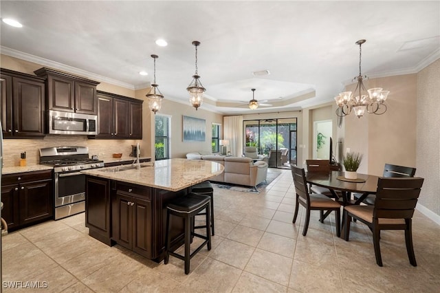 kitchen featuring a raised ceiling, stainless steel appliances, sink, dark brown cabinets, and ceiling fan with notable chandelier