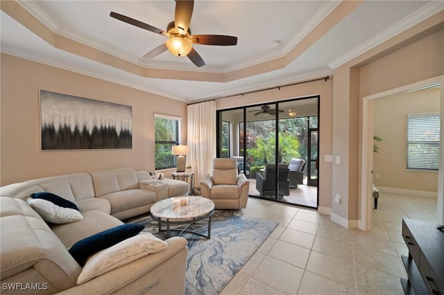 living room with light tile patterned floors, ceiling fan, ornamental molding, and a tray ceiling