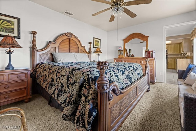 carpeted bedroom with ceiling fan, ensuite bathroom, and sink