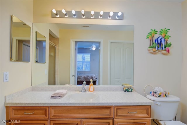 bathroom featuring vanity, a shower with door, toilet, and ceiling fan