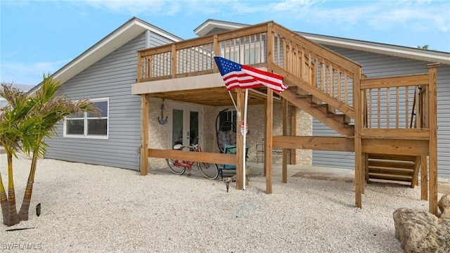 back of property with a wooden deck, a patio area, and french doors