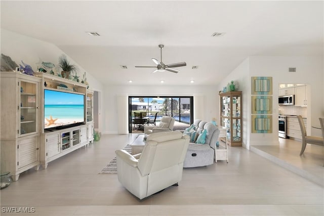 living room featuring lofted ceiling, ceiling fan, and visible vents