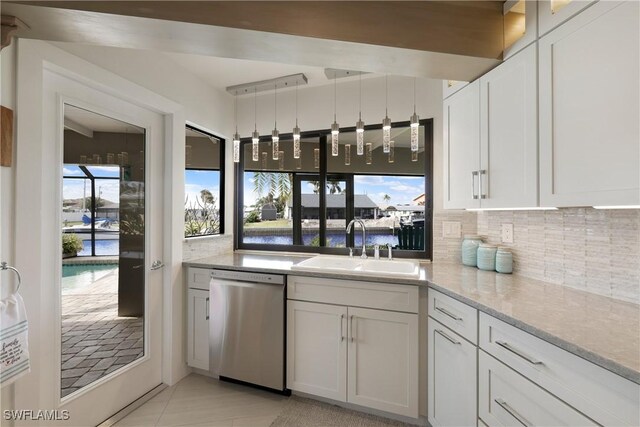 kitchen with stainless steel dishwasher, backsplash, a sink, and white cabinets