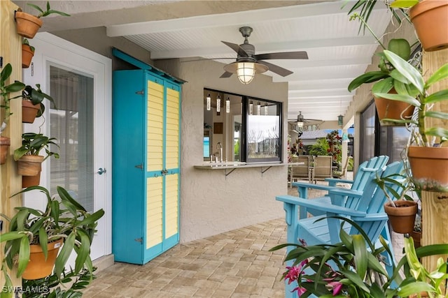 sunroom with a sink, a ceiling fan, and beam ceiling