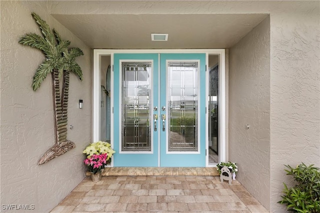 entrance to property featuring french doors and stucco siding