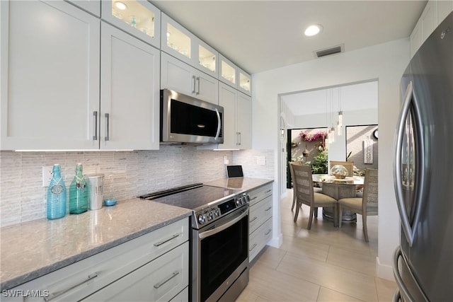 kitchen with tasteful backsplash, visible vents, appliances with stainless steel finishes, white cabinetry, and light stone countertops