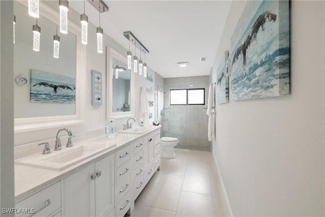 bathroom featuring double vanity, toilet, a sink, tile patterned flooring, and tiled shower