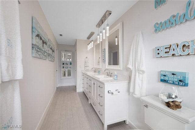 full bath with baseboards, a sink, toilet, and double vanity