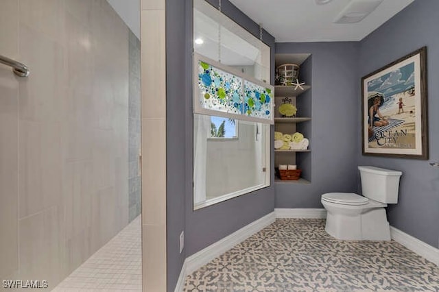 bathroom featuring toilet, a tile shower, and built in shelves