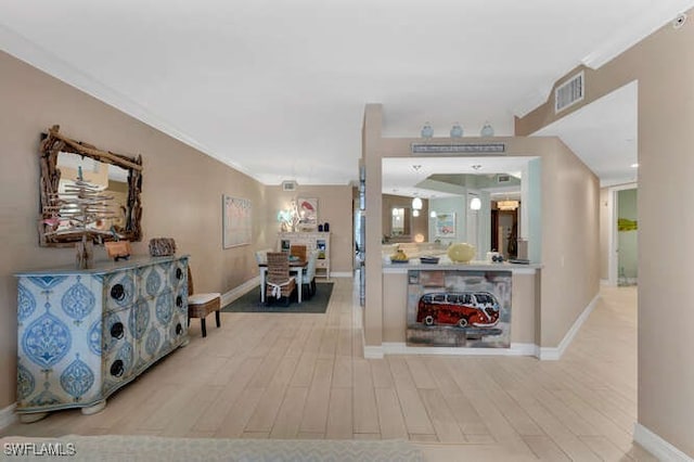 hallway with light hardwood / wood-style flooring and ornamental molding