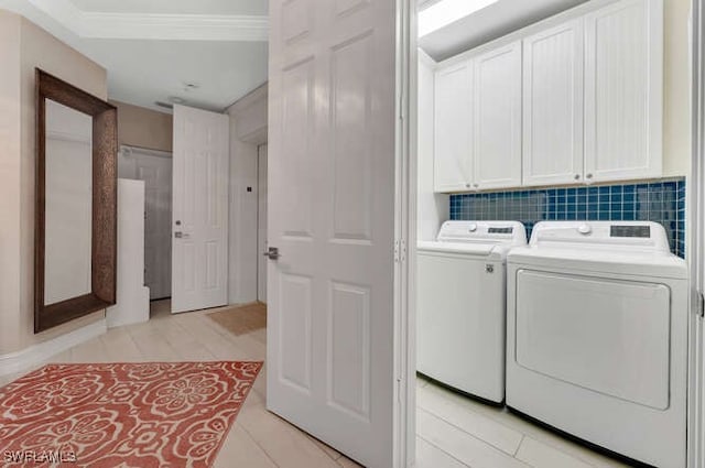 clothes washing area with washing machine and clothes dryer, light tile patterned floors, and cabinets