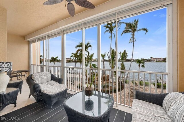 sunroom / solarium with ceiling fan and a water view