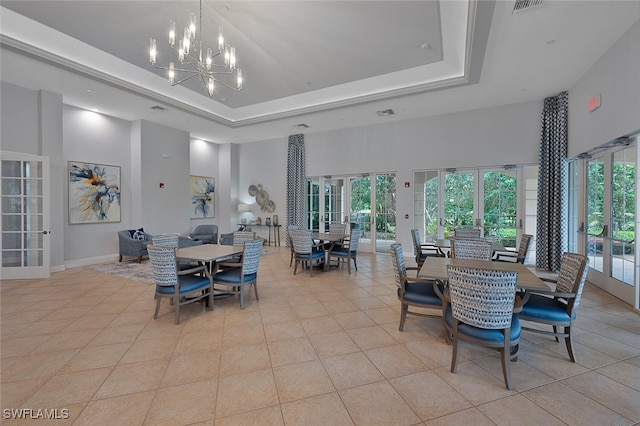 tiled dining area with a tray ceiling, french doors, a high ceiling, and an inviting chandelier