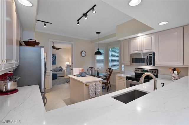 kitchen with sink, hanging light fixtures, rail lighting, appliances with stainless steel finishes, and light stone counters