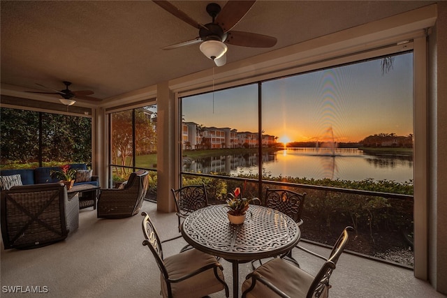 sunroom with ceiling fan and a water view