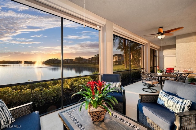 sunroom / solarium with ceiling fan and a water view