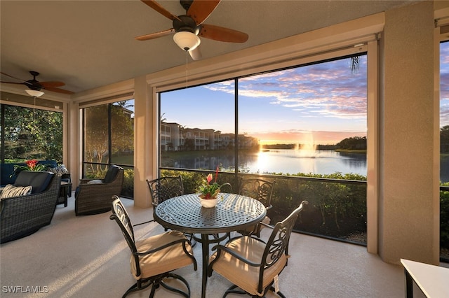 sunroom featuring a water view and ceiling fan