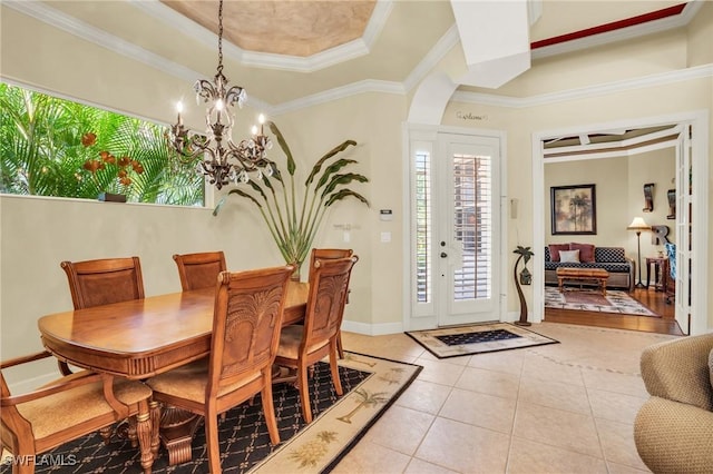 tiled dining space featuring an inviting chandelier, a raised ceiling, and ornamental molding