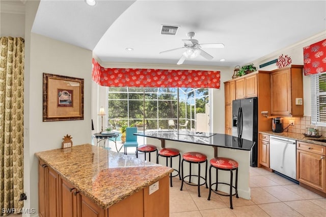 kitchen with dishwasher, a center island, and light stone countertops