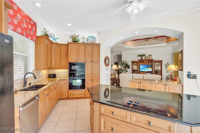 kitchen featuring sink, dark stone countertops, light tile patterned floors, black appliances, and ornamental molding