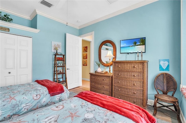 bedroom with wood-type flooring, ornamental molding, and a closet