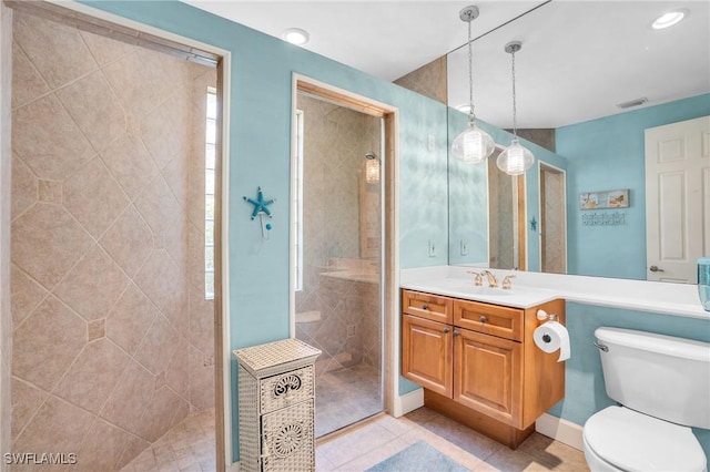 bathroom with a tile shower, tile patterned flooring, vanity, and toilet