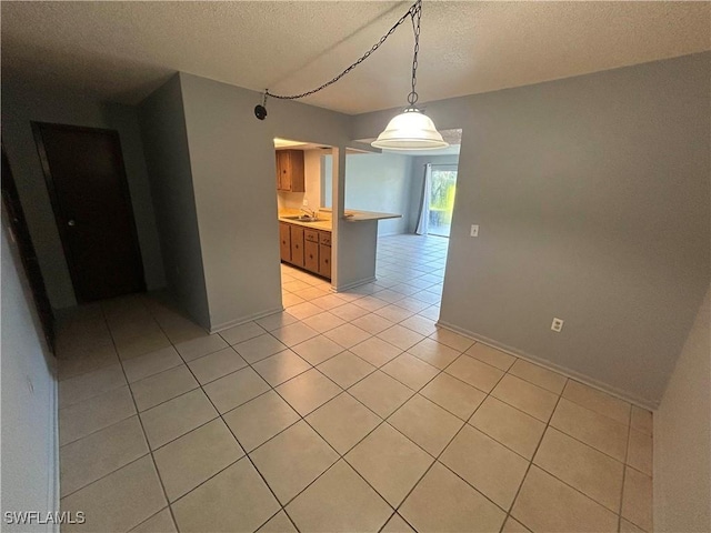 tiled empty room featuring sink and a textured ceiling