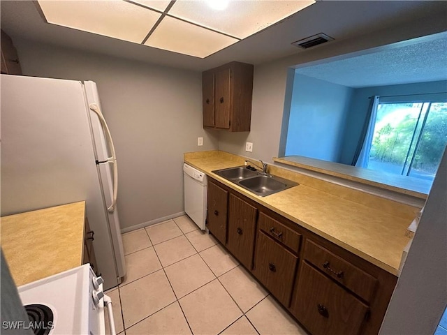 kitchen with white appliances, sink, light tile patterned floors, dark brown cabinets, and kitchen peninsula