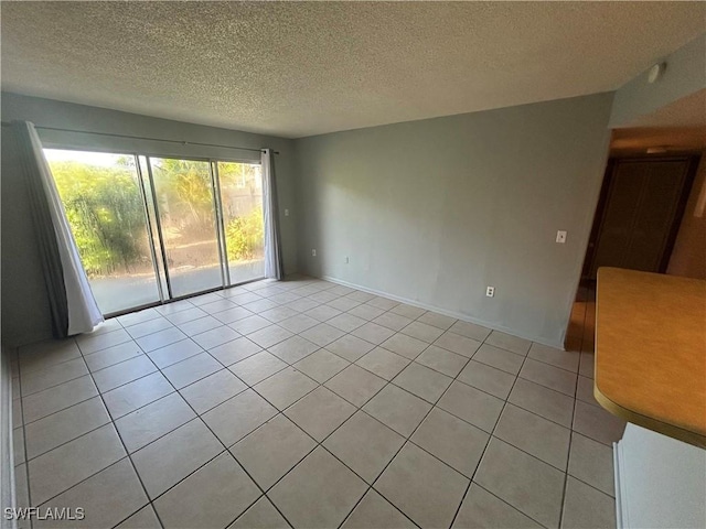 spare room featuring light tile patterned floors and a textured ceiling