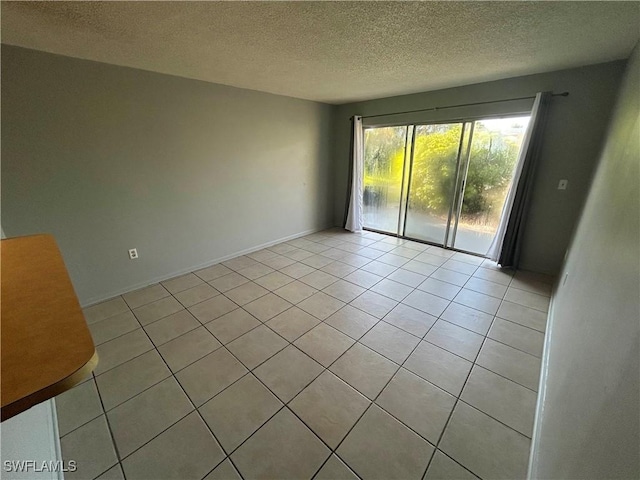 spare room featuring a textured ceiling and light tile patterned flooring