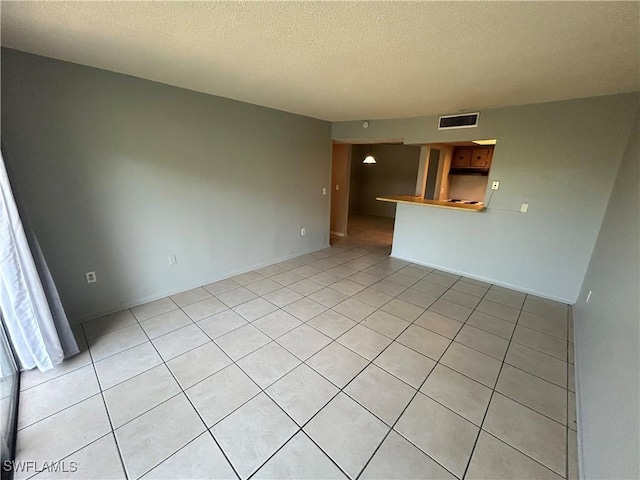 spare room featuring light tile patterned floors and a textured ceiling