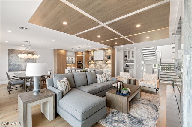 living room with light hardwood / wood-style floors, a notable chandelier, and wood ceiling