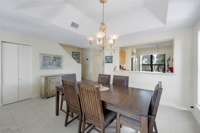 tiled dining area with a raised ceiling and a chandelier